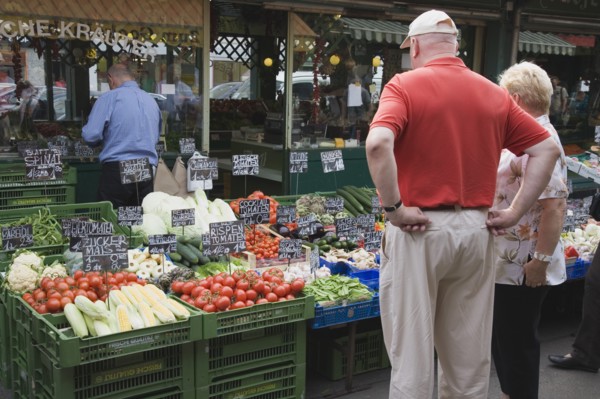 Vienna, Austria. The Naschmarkt. Tourists looking at display on fresh produce stall in front of