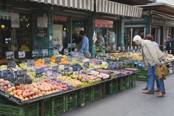 Vienna, Austria. The Naschmarkt. Customers at fresh produce stall looking at display that includes