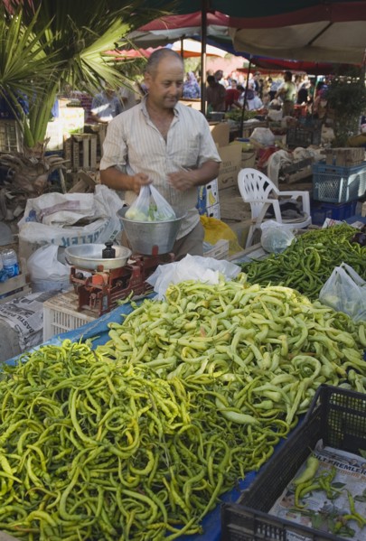 Kusadasi, Aydin Province, Turkey. Turkish stallholder selling green chilis under shade in town