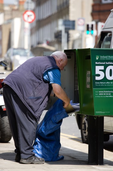 Ireland, County Dublin, Dublin City, An Post Irish postal worker emptying mail from a green modern