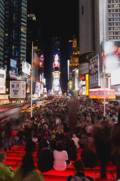 USA, New York, New York City, Manhattan  People sitting on lit red steps or walking at night in