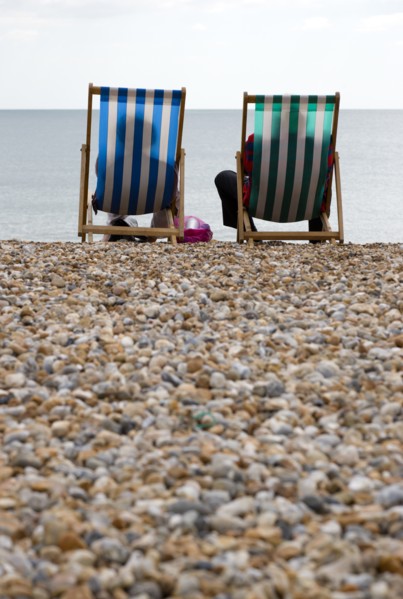 England, West Sussex, Bognor Regis, Two elderly seniors sitting on deck chairs on the pebble