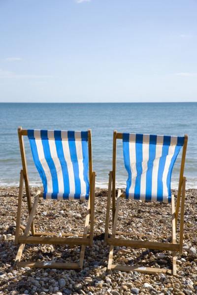 England, West Sussex, Bognor Regis, Two blue and white deck chair on the shingle pebble beach