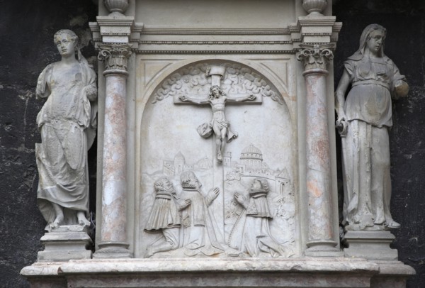 Stone relief carving of the crucifixion flanked by statues on the outside of the Stephansdom