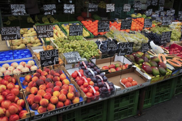 Fruit stall in the Naschmarkt with display of produce including peaches plums grapes and mangoes.
