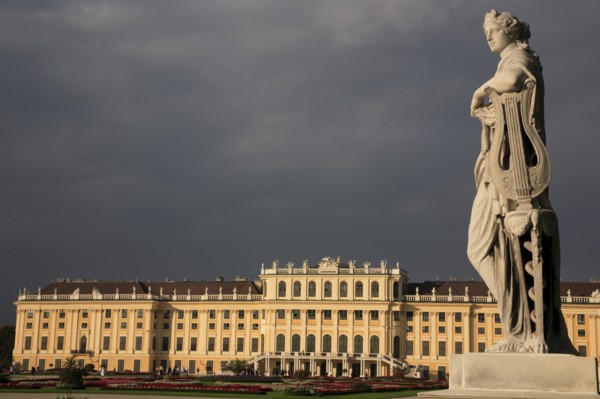Schonnbrunn Palace. Exterior with statue of standing figure in foreground beneath grey stormy sky.