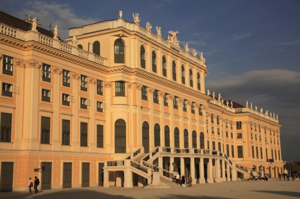 Schonnbrunn Palace. Part view of exterior facade with tourist visitors in courtyard in foreground.