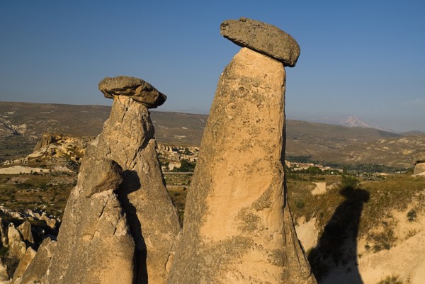 Urgup. Fairy chimney rock formations with Mount Erciyes in the background in warm golden light.