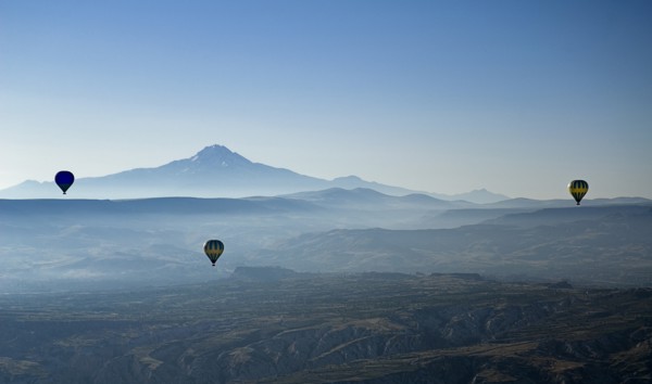 Early morning with hot air balloons in flight mist drifting across landscape and Mount Erciyes in