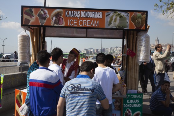 Turkey, Istanbul, Eminonu Ice cream vendor outside the New Mosque with young men waiting to be