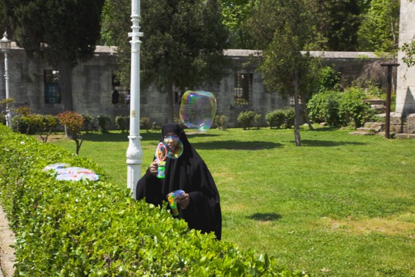 Turkey, Istanbul, Sultanahmet woman selling bubvble gun machine in park outside the Blue Mosque.