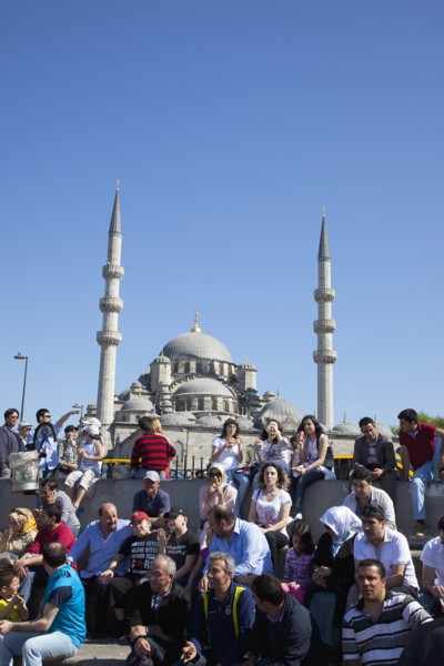 Turkey, Istanbul, Eminonu Yeni Camii New Mosque people on sat on steps next to the subway. 
Photo