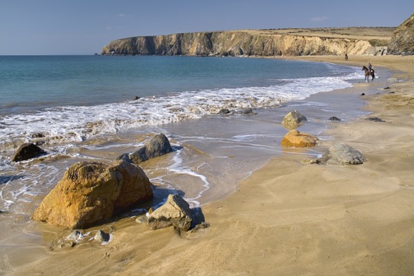 Ireland, County Waterford, Tramore, Kilfarrasy Beach and coastline with people riding horseback.