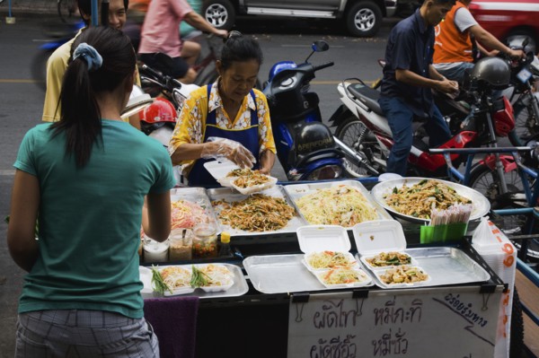 Street vendor and daughter sell take away Pad-thai the national fried noodle classic dish.