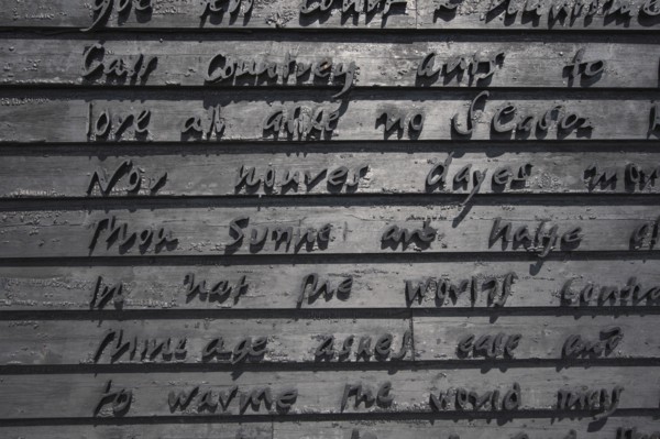 Detail of building gable wall with words carved from wood.
