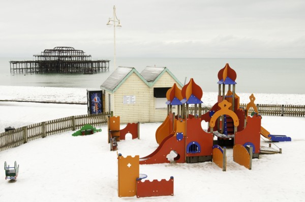 West Pier during winter with snow on the beach and childrens play area in the foreground.