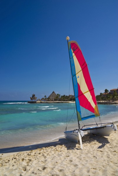 View along beach with colourful hobie cat.