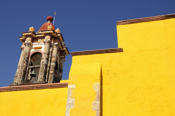 Mexico, Bajio, San Miguel de Allende, Part view of bright yellow exterior wall and church bell