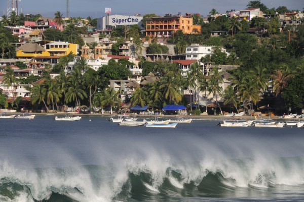 Mexico, Oaxaca, Puerto Escondido, Playa Principal Breaking waves and boats overlooked by buildings