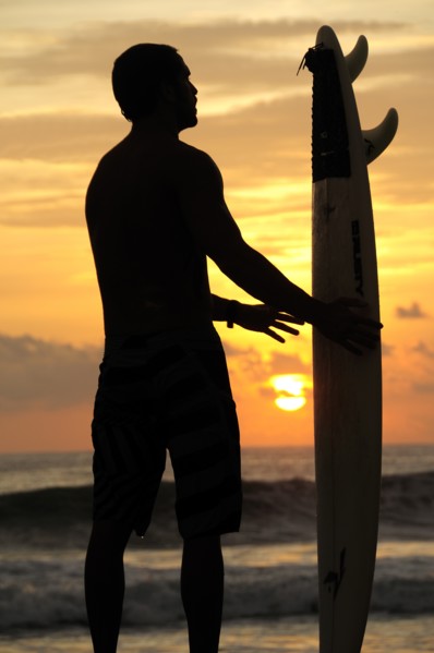 Mexico, Oaxaca, Puerto Escondido, Surfer and board silhouetted at sunset on Playa Zicatela. Photo :