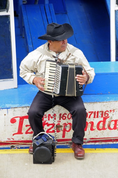 Mexico, Michoacan, Patzcuaro, Lago Patzcuaro Musician playing the accordion sitting on painted boat