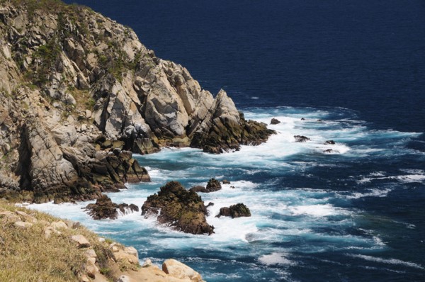Mexico, Oaxaca, Huatulco, Waves breaking against rocky coastline.. Photo : Nick Bonetti