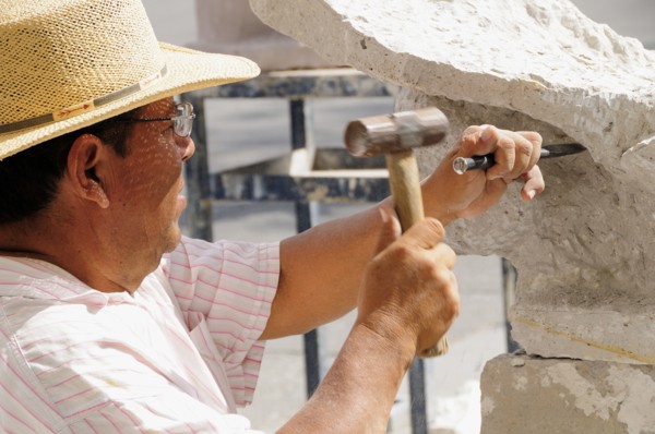 Mexico, Jalisco, Guadalajara, Plaza de la Liberacion Sculptor working stone with hammer and chisel.