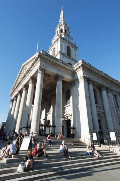 England, London, Trafalgar Square tourists sat on the steps of St Martin in the Fields Church.