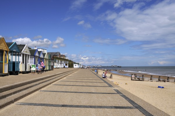 England, Suffolk, Southwold, Beach Huts near the pier with Sea Defences and Holidaymakers. Photo :