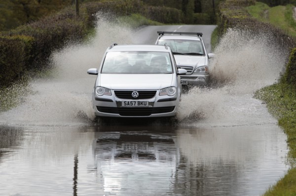 England, Kent, Flooding, Flooded country road with cars driving slowly through waters. Photo : Sean