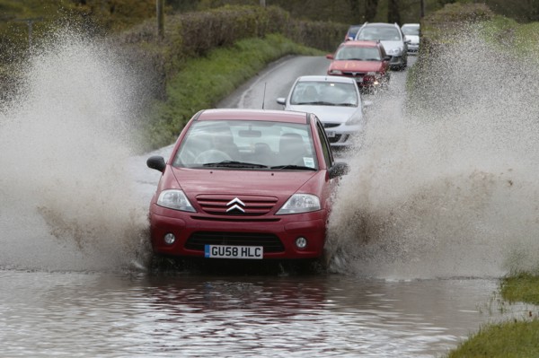 England, Kent, Flooding, Flooded country road with cars driving slowly through waters. Photo : Sean