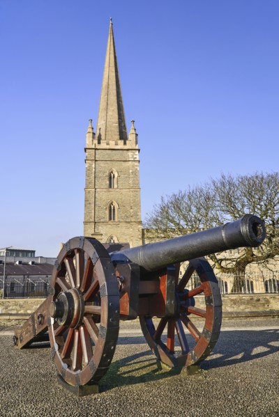Ireland, North, Derry, St Columb's Cathedral with cannon on city walls in the foreground. 
Photo