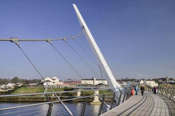 Ireland, North, Derry, The Peace Bridge over the River Foyle opened in 2011 with the former Ebrington Barracks in the background.