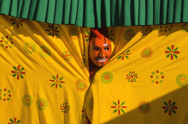 Bhutan, Thimpu Dzong, Atsara, or comedian peering out from behind a curtain at a masked dance