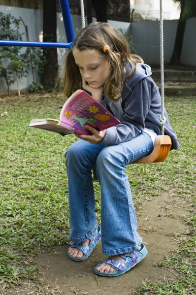 Education, Children, Reading, 10 year old girl reading on swing in garden. 
Photo NIc I Anson