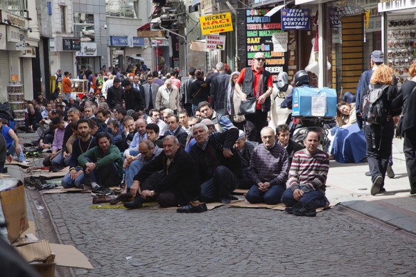 Turkey, Istanbul, Fatih, Sultanahmet, Men sat in street in readiness for midday prayers. 
Photo