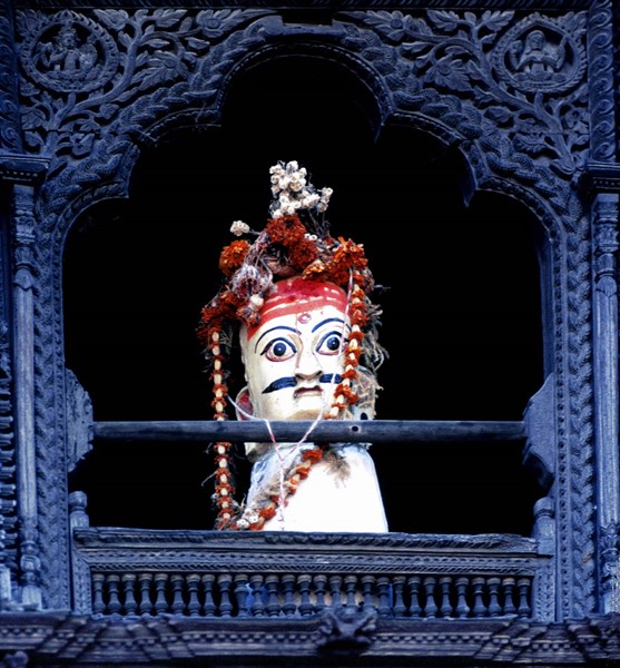 Curious idol in intricately carved window, Bhaktapur, Nepal, India.