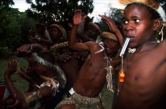 Zulu boy blowing on a whistle, dancers in the background