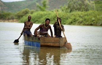 HIMBA IN CRAFT ON KUNENE RIVER, NAMIBIA