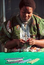A Xhosa speaking worker creates a necklace from beads at Umtha Beads, a craft business run by David