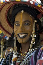 A Wodaabe man performs a dance of male beauty, showing off the whiteness of his teeth and eyes at a