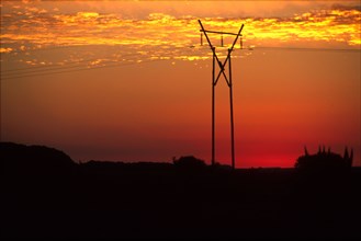 sunset in the karoo behind an electricity pylon