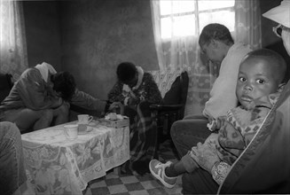 Caregivers pray for sick daughter while mother and the daugher's child look on