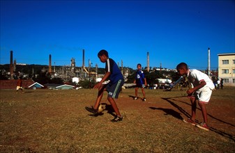 boys playing soccer with factories behind