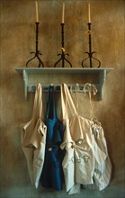 portrait view of aprons hanging from a shelf with candlesticks
