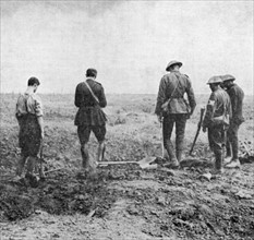 World War I: Army chaplain conducting burial service in the field while burial party stand, paying their respects