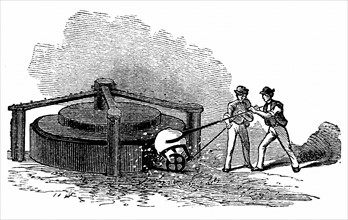 Ouvriers placant une boule de marcassite brulante dans la machine a mouler rotative a serrage par pression