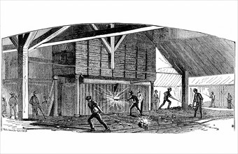 Travail du fer : ouvriers transportant des boules de fer du four jusqu'a la machine a mouler a serrage par pression