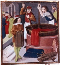 Des teinturiers plongent un pan de tissu dans une bassine de teinture placée sur le feu