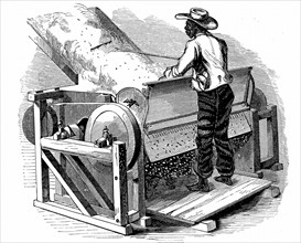 Saw gin for cleaning cotton being operated by barefoot black labourer